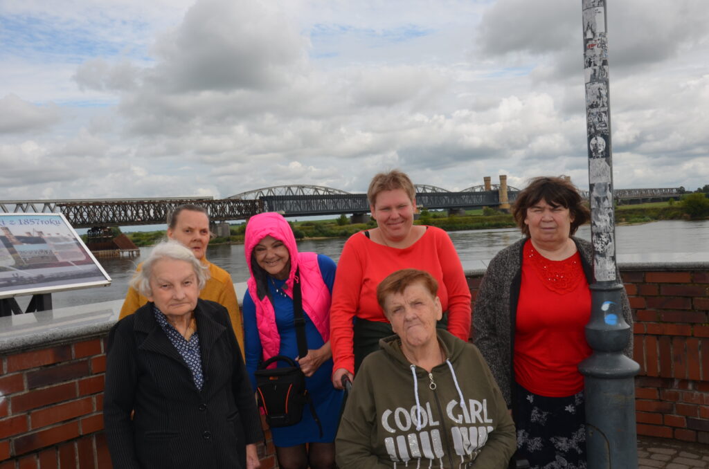 Grupa sześciu pań pozuje do zdjęcia, uśmiecha się , w tle most tczewski i Wisła